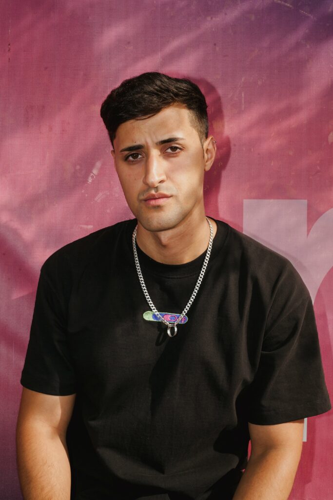 Der Künstler Rang Haider vor einem rosaroten Hintergrund.